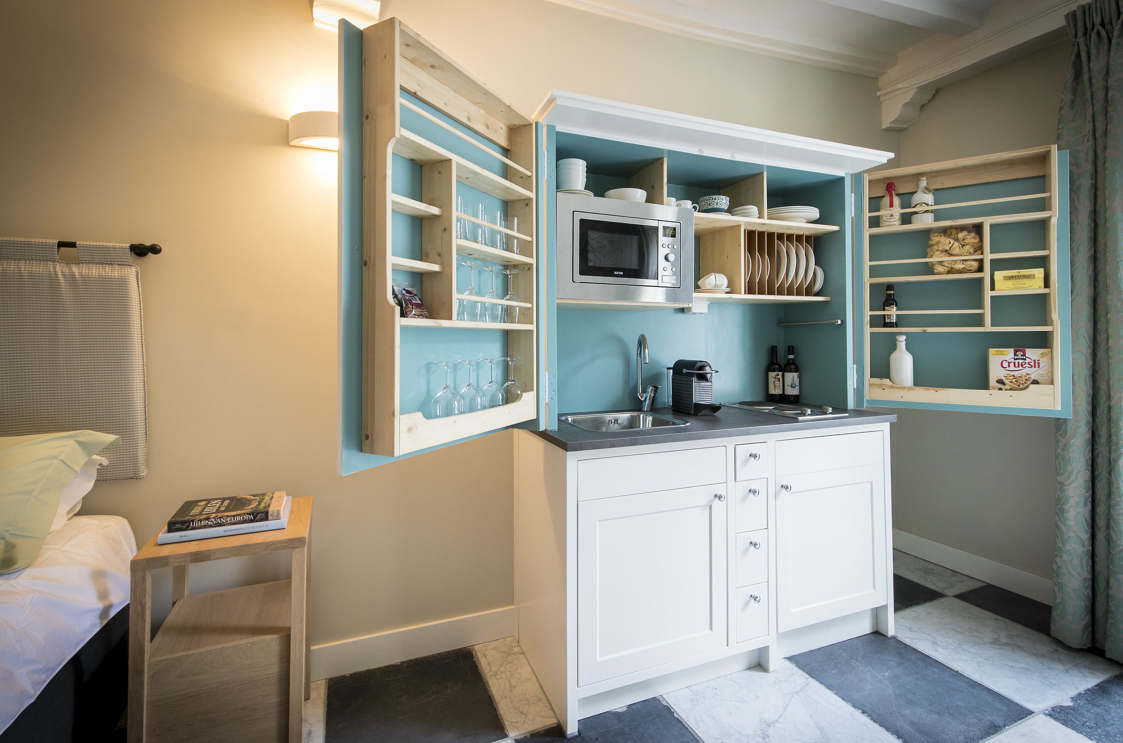 A compact kitchen with a built-in microwave, white cabinets, and a sink.
