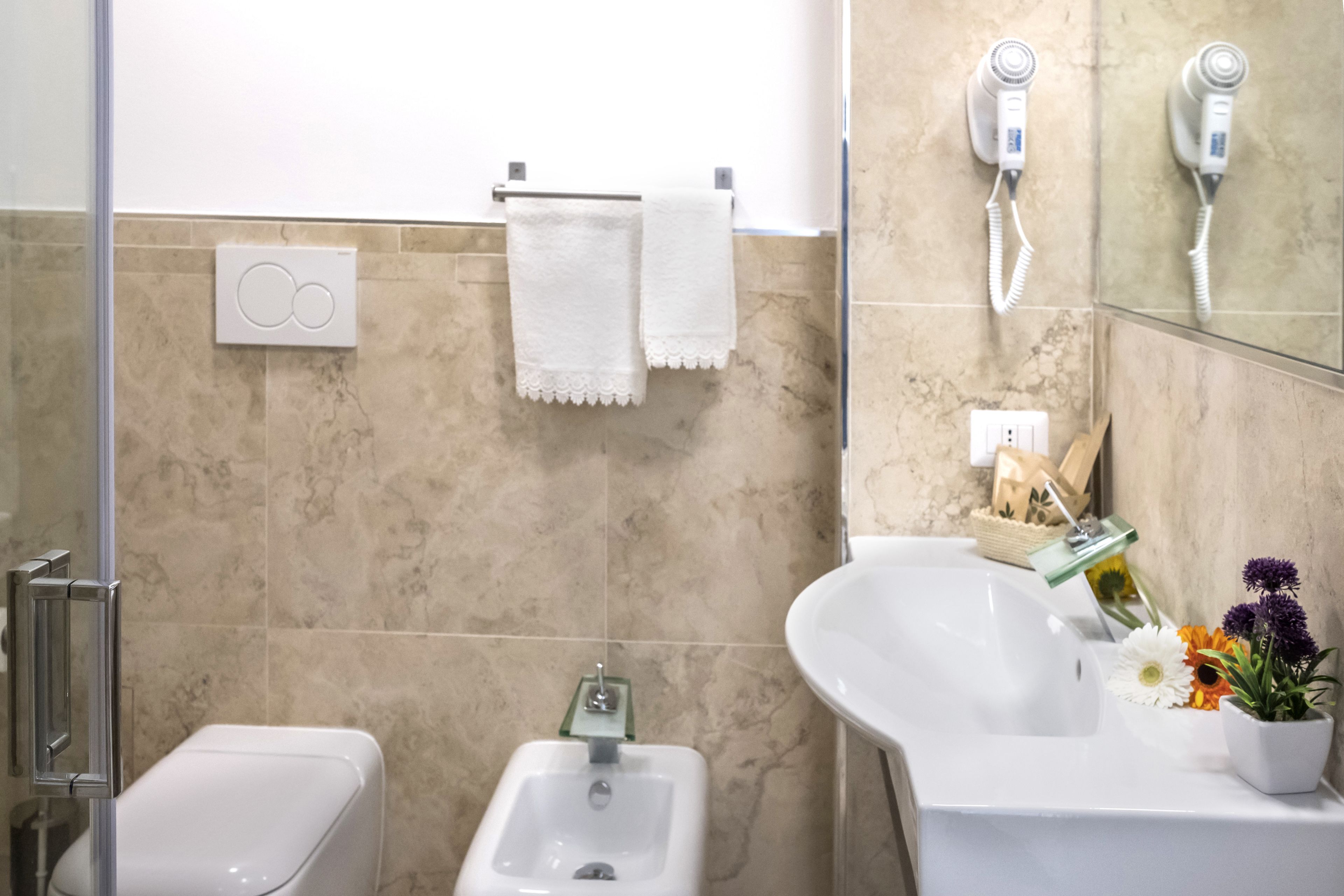 Ein Badezimmer mit einer Bidet-Funktion, einem Waschbecken, einem Spiegel und einem Handtuchhalter.
