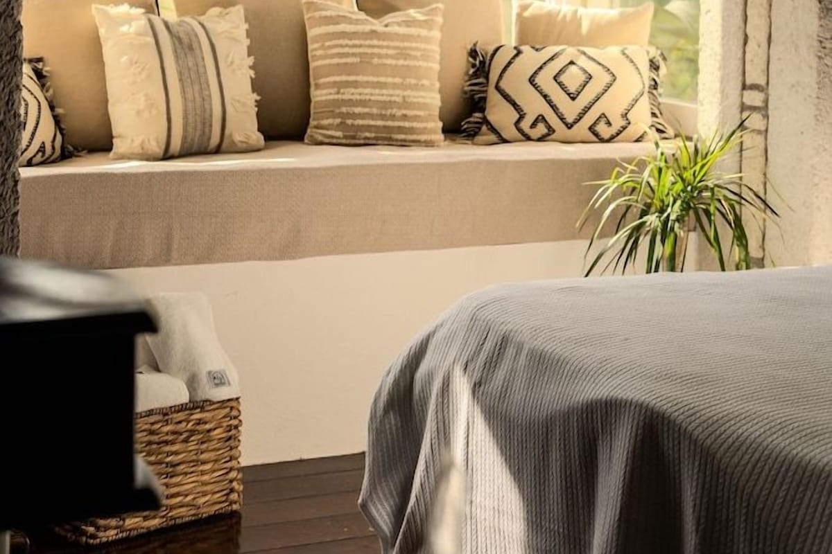A room with a window seat, a ceiling light, and a potted plant.