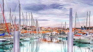 Un puerto deportivo con barcos amarrados, un banco de madera y vistas de edificios al fondo.