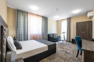 Una habitación de hotel con cama, sofá, escritorio y armario.