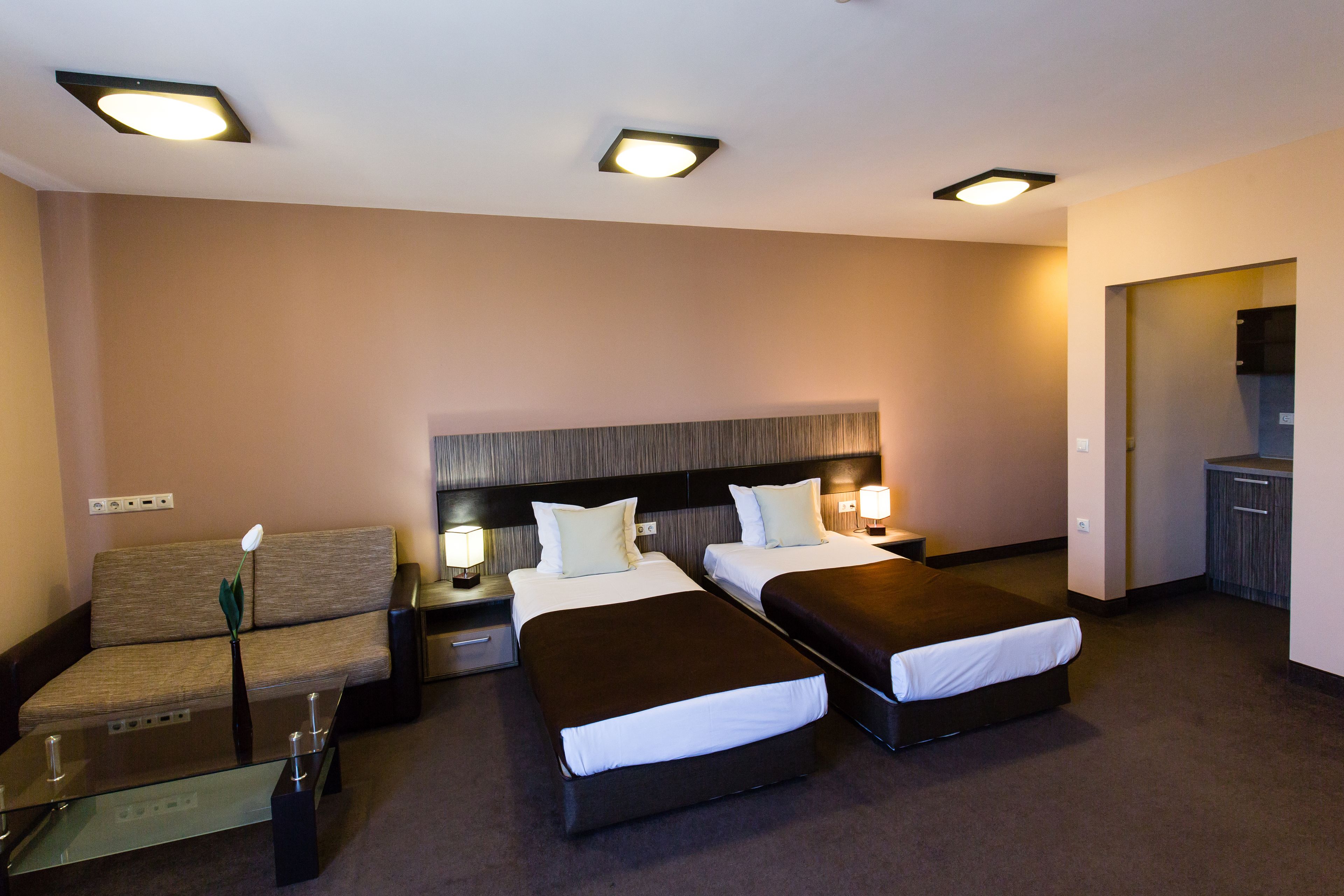Une chambre d’hôtel avec deux lits, un canapé, une petite table et un téléviseur.
