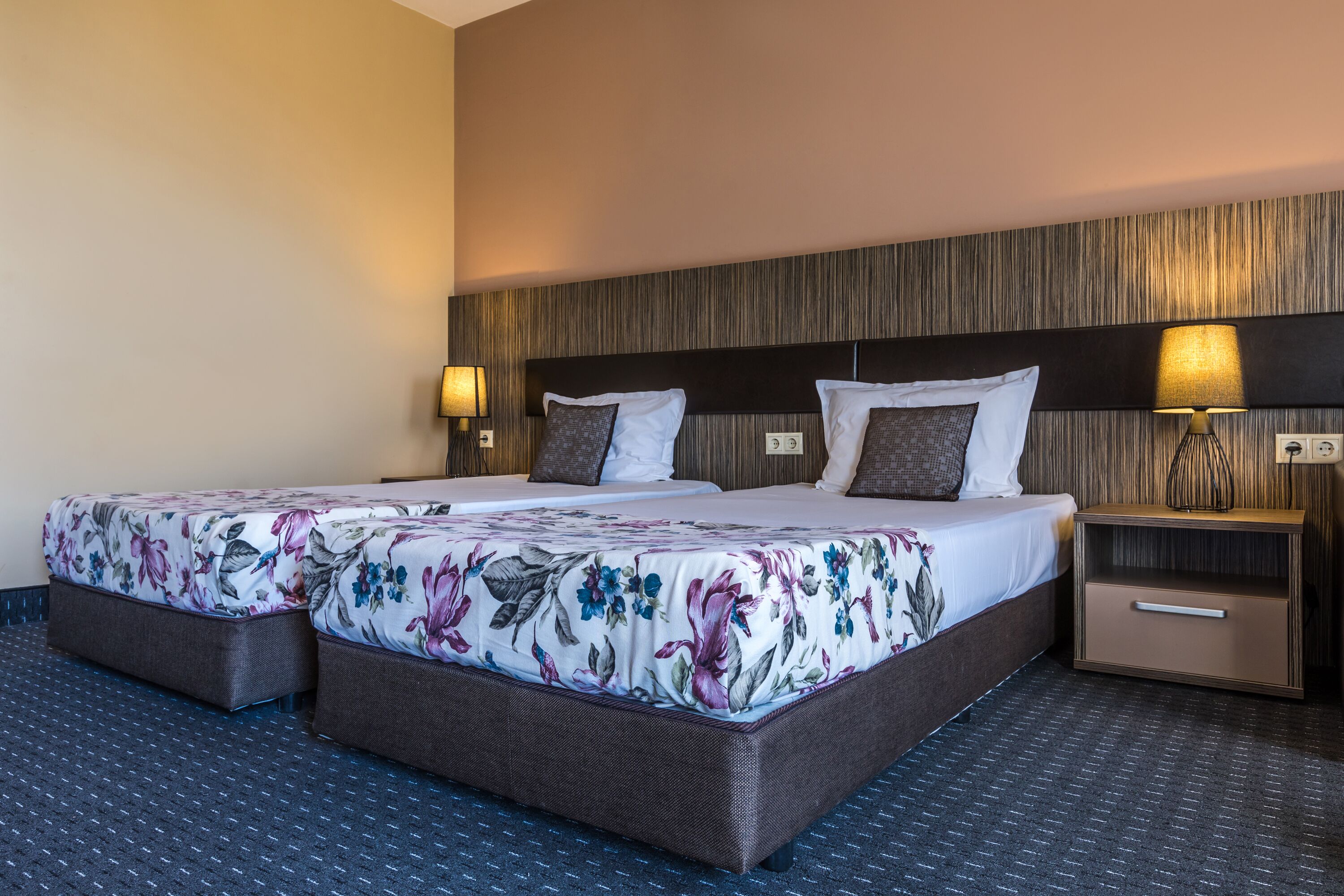 A hotel room with a large bed, two bedside tables, and a nightstand.