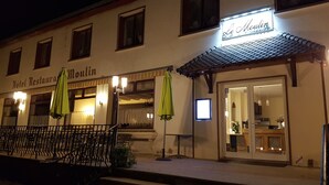 Un hotel llamado "Hotel Restaurant Moulin" con terraza y sombrillas.
