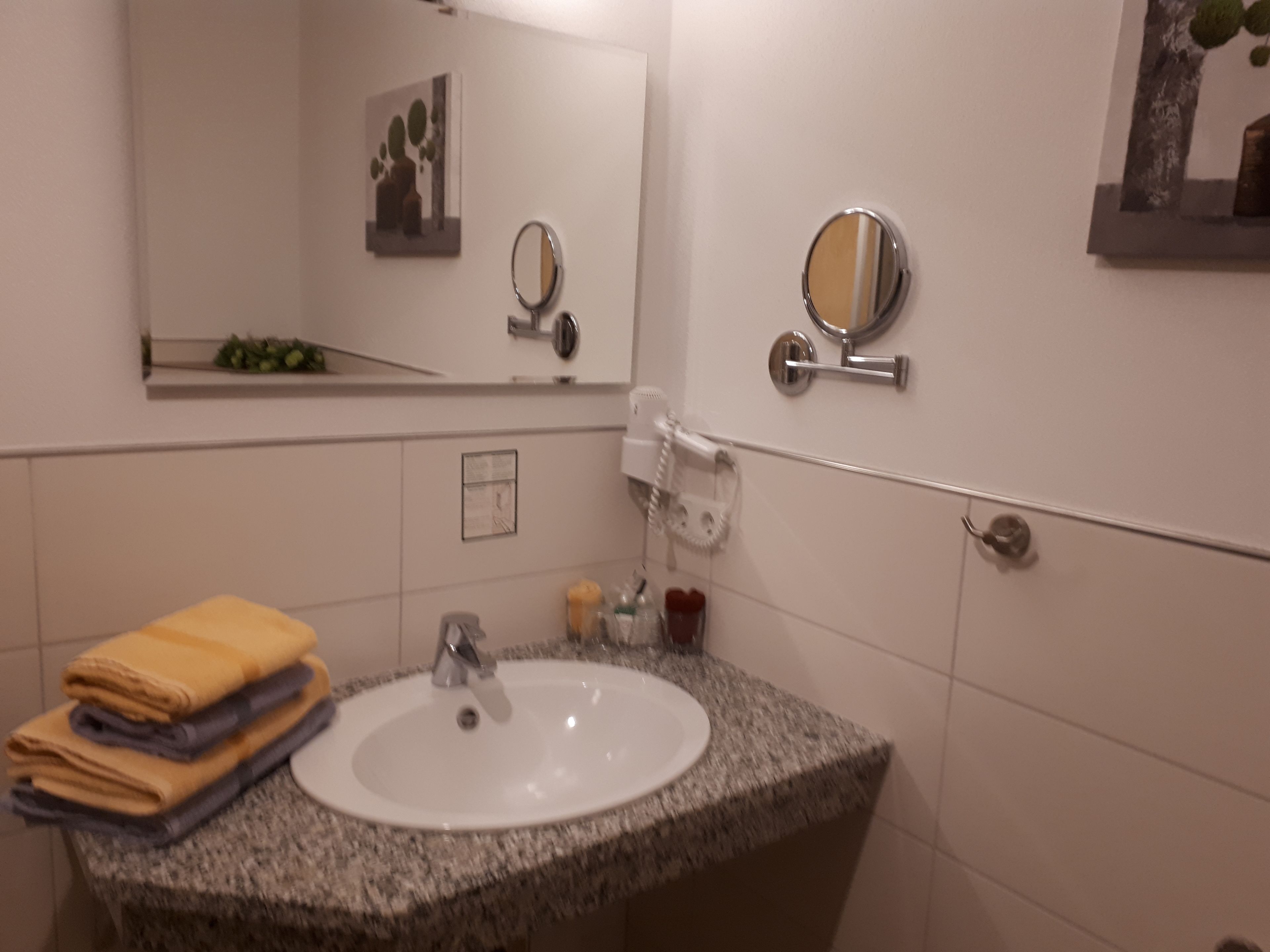 A bathroom with a granite sink, a mirror, a towel rack, and a wall-mounted telephone.