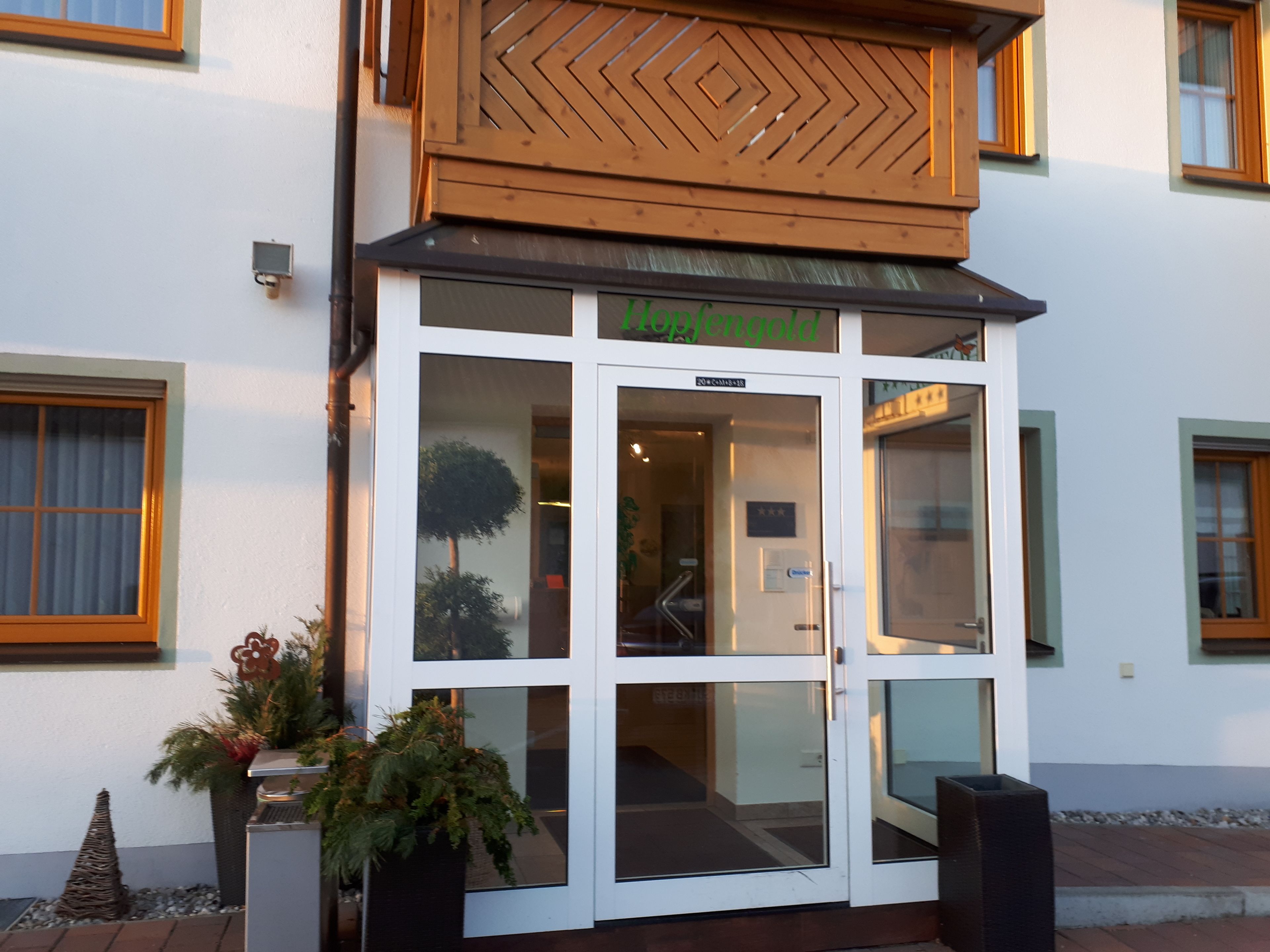 En hotellentrél med en glasdörr, en träfasad och en skylt ovanför dörren.
