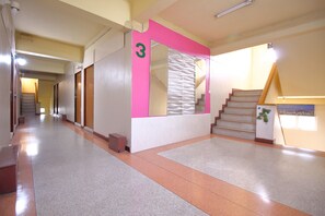 Un pasillo con una escalera, un cartel con el número 3 y una planta en la pared.