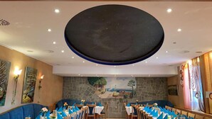 Un restaurant doté d’un grand plafond circulaire remarquable, de murs en pierre et d’une décoration de table aux tons bleus.