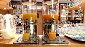 Un espace bar équipé de deux extracteurs de jus qui distribuent du jus d’orange dans des verres, d’un pichet de lait et d’un plateau rempli de verres.