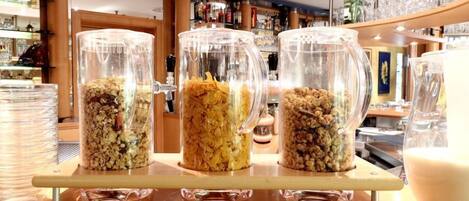 Três recipientes de vidro transparentes sobre um suporte de madeira, cada um com tipos diferentes de granola.