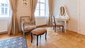 A room with a wooden floor, a chair, a desk with a mirror, and a window with curtains. - ElegantVienna Apartments (Vienna)