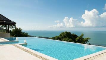 Relax by the serene infinity pool overlooking the ocean and distant land.