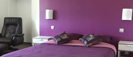 A room with a large bed, a chair, and two bedside tables.