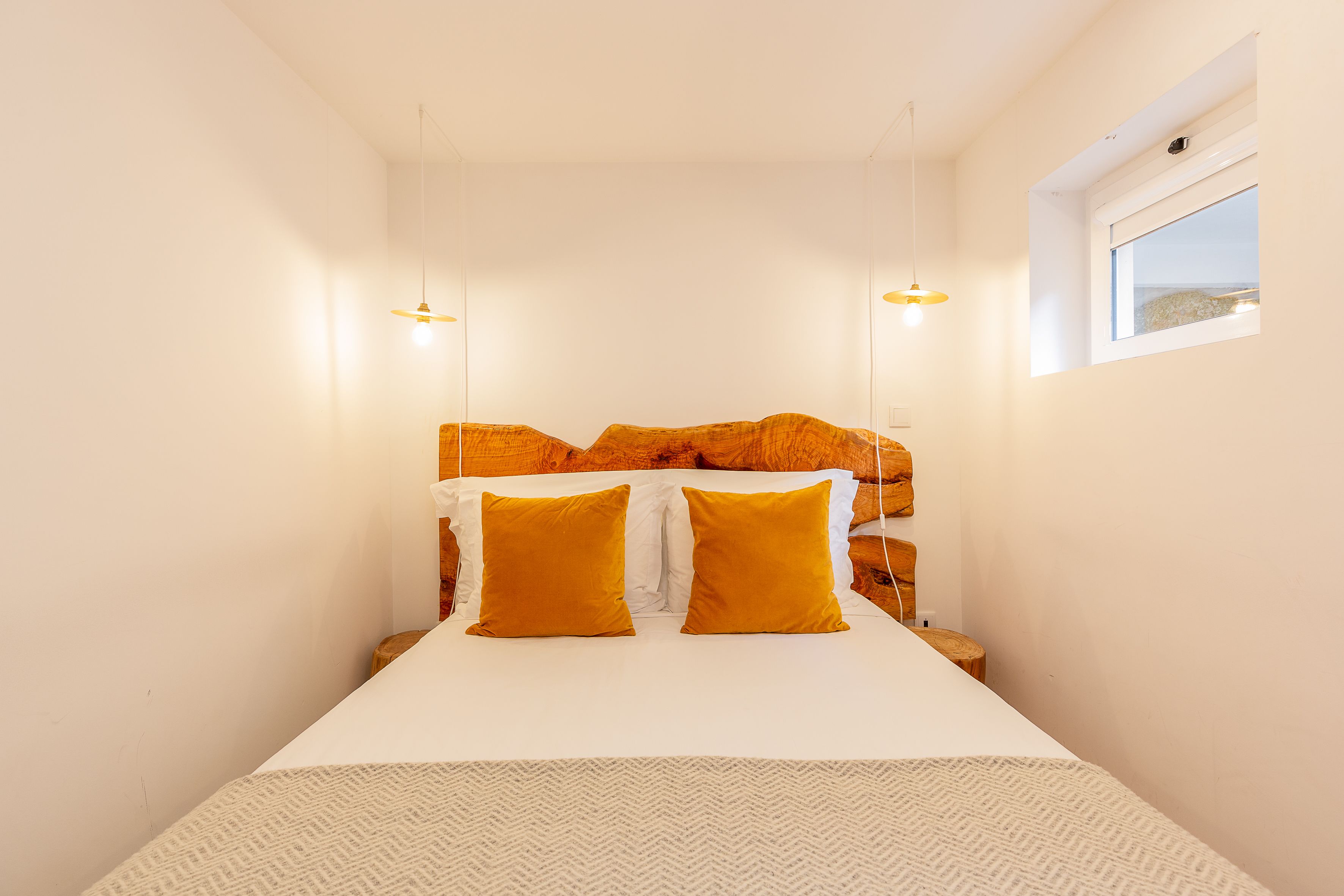 A bedroom with a bed, two bedside lamps, a window, and a headboard.