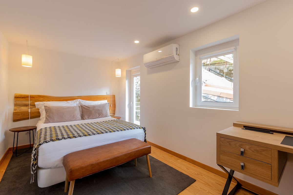 Ein Schlafzimmer mit einem Bett, Nachttischen, einem Schreibtisch und einer Klimaanlage.
