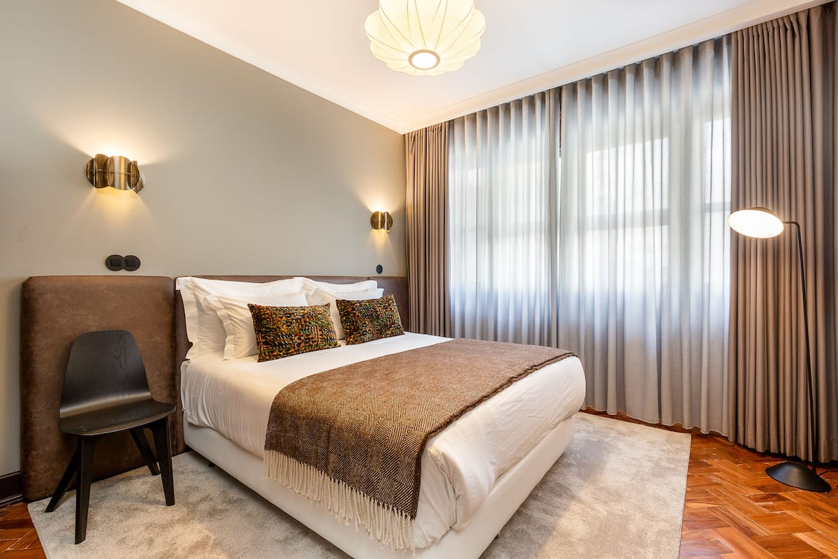 Een moderne slaapkamer met een groot bed, een stoel, een bureau en een lamp.