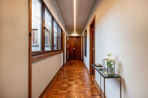 Un pasillo con suelo de madera, una vitrina de vidrio con una orquídea y una puerta al final.