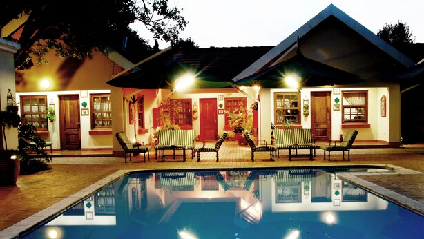 A swimming pool with lounge chairs and a building with multiple doors and windows.