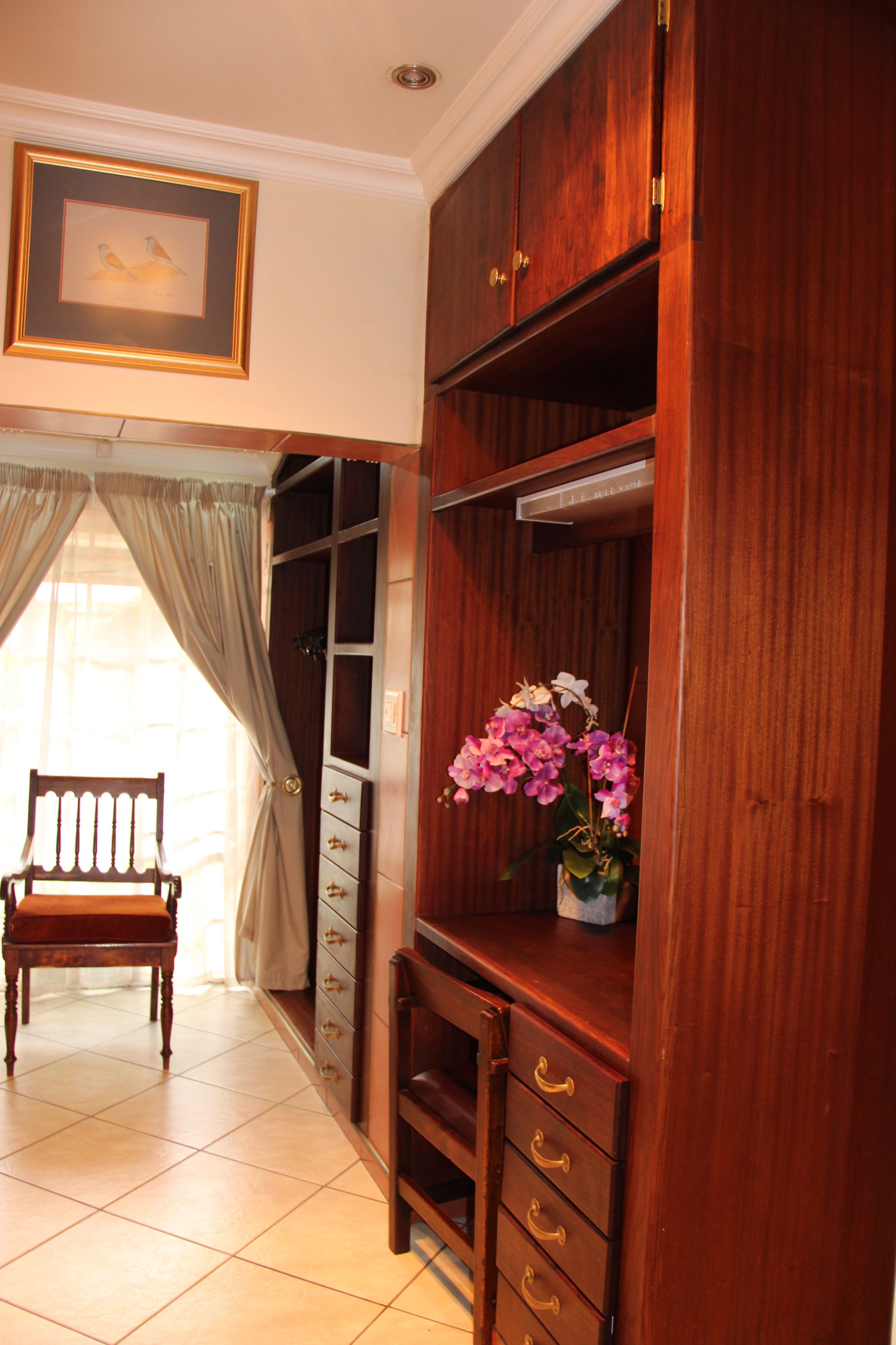 A room with a wooden cabinet, a chair, and a window with curtains.