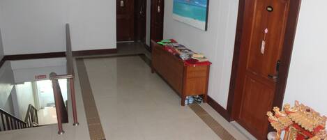 A hotel lobby with a staircase, a reception desk, a painting, and a door.
