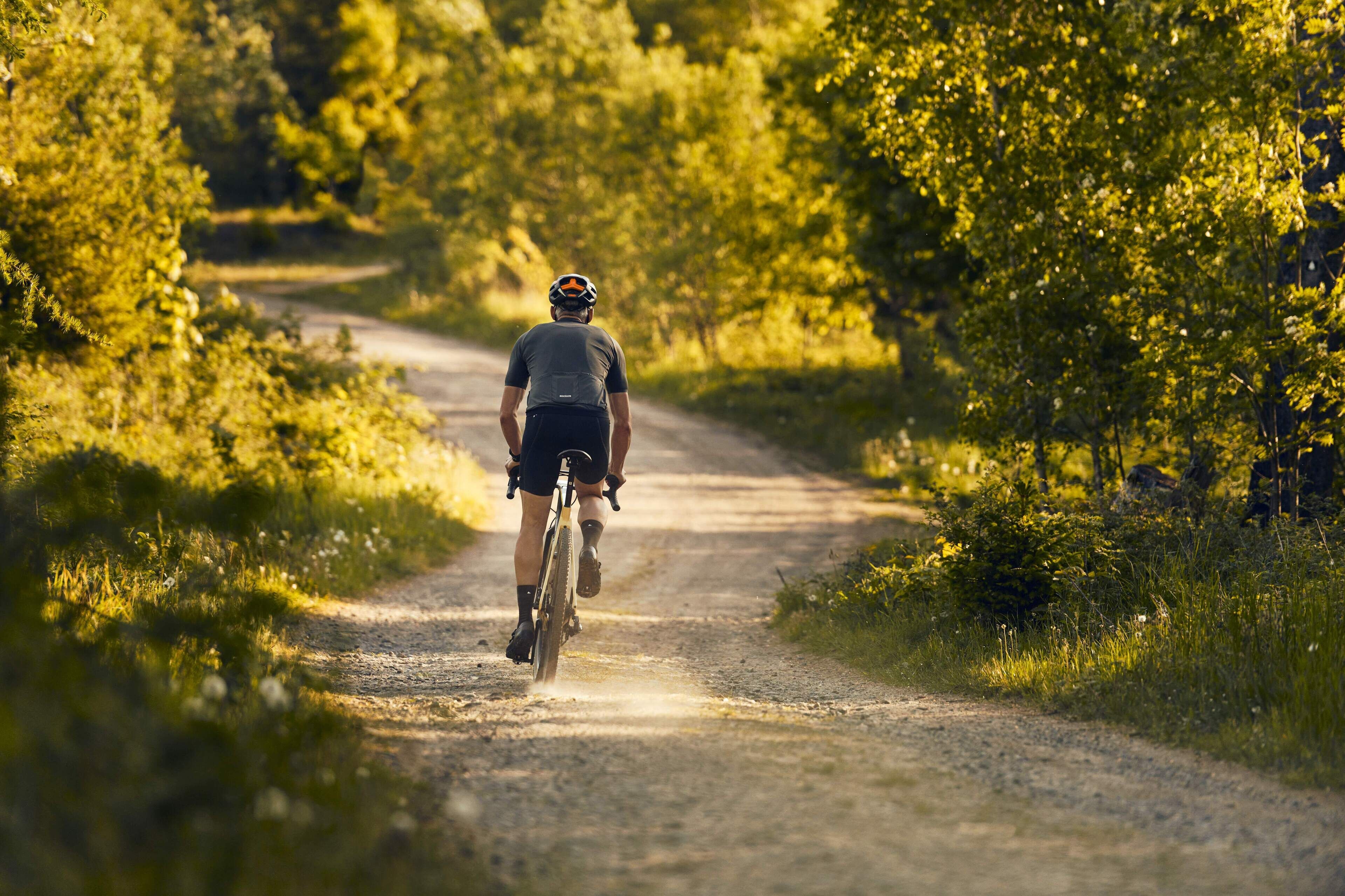 Ein Radfahrer auf einem Schotterweg, umgeben von viel Grün.