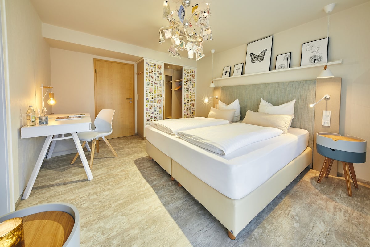 Quarto de hotel moderno com uma cama grande, uma escrivaninha e um guarda-roupa.