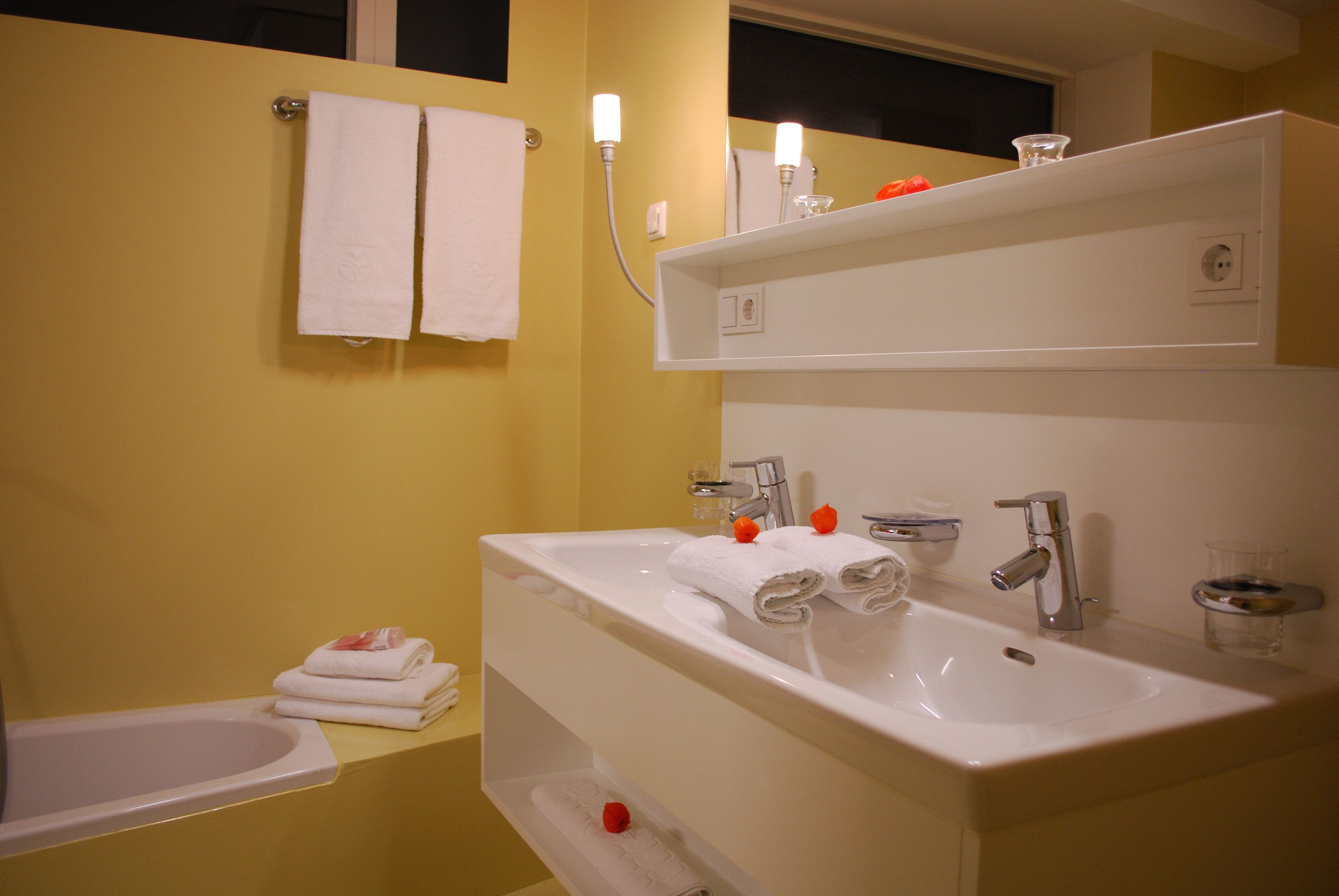 Un baño con un lavabo blanco, un espejo y un toallero.