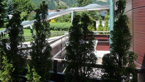 A view of a mountain range with a bridge in the distance, surrounded by greenery and trees. - SUN Matrei Apartments (Matrei in Osttirol)