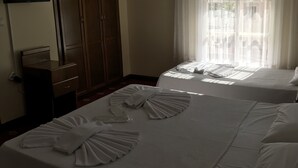 Een hotelkamer met twee bedden, een kledingkast, een televisie en een raam met dunne gordijnen.