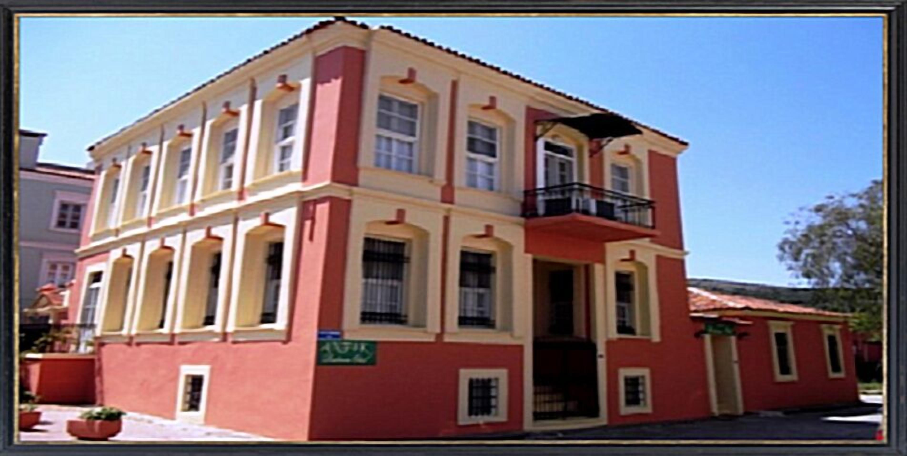 A red and yellow building with a balcony, a sign indicating a restaurant, and a small attached structure.