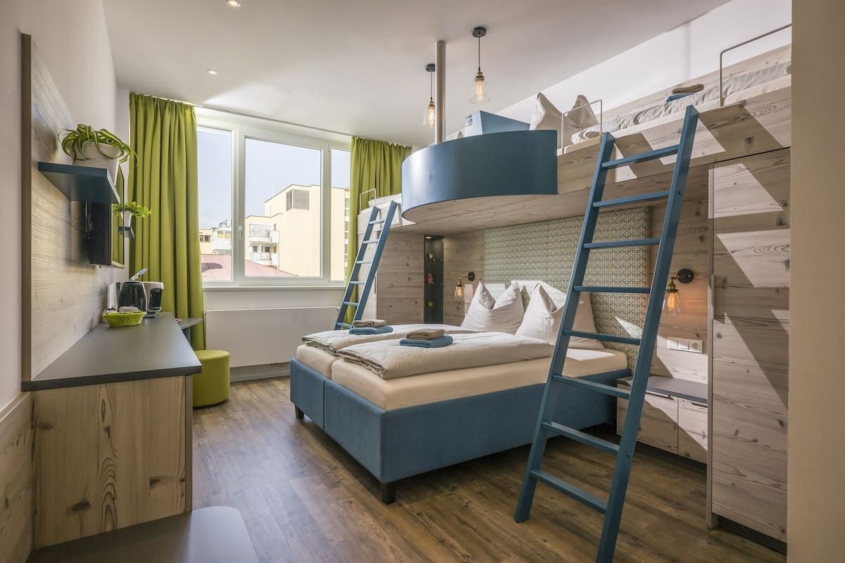 Ein kleines Schlafzimmer mit Etagenbett, Schreibtisch und einem Fenster mit Vorhängen.