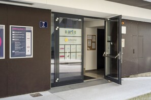 A modern building entrance with a glass door, a sign for 'INNGASSE 7', and a 'BACK TO THE BOARDINGHOUSE' sign. - Backstage Kufstein (Kufstein)