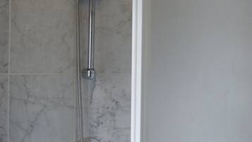 A shower with a handheld showerhead and a wall-mounted faucet.