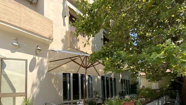 A courtyard with a seating area, potted plants, and a large umbrella. - Hotel Naviglio (Pietrasanta)
