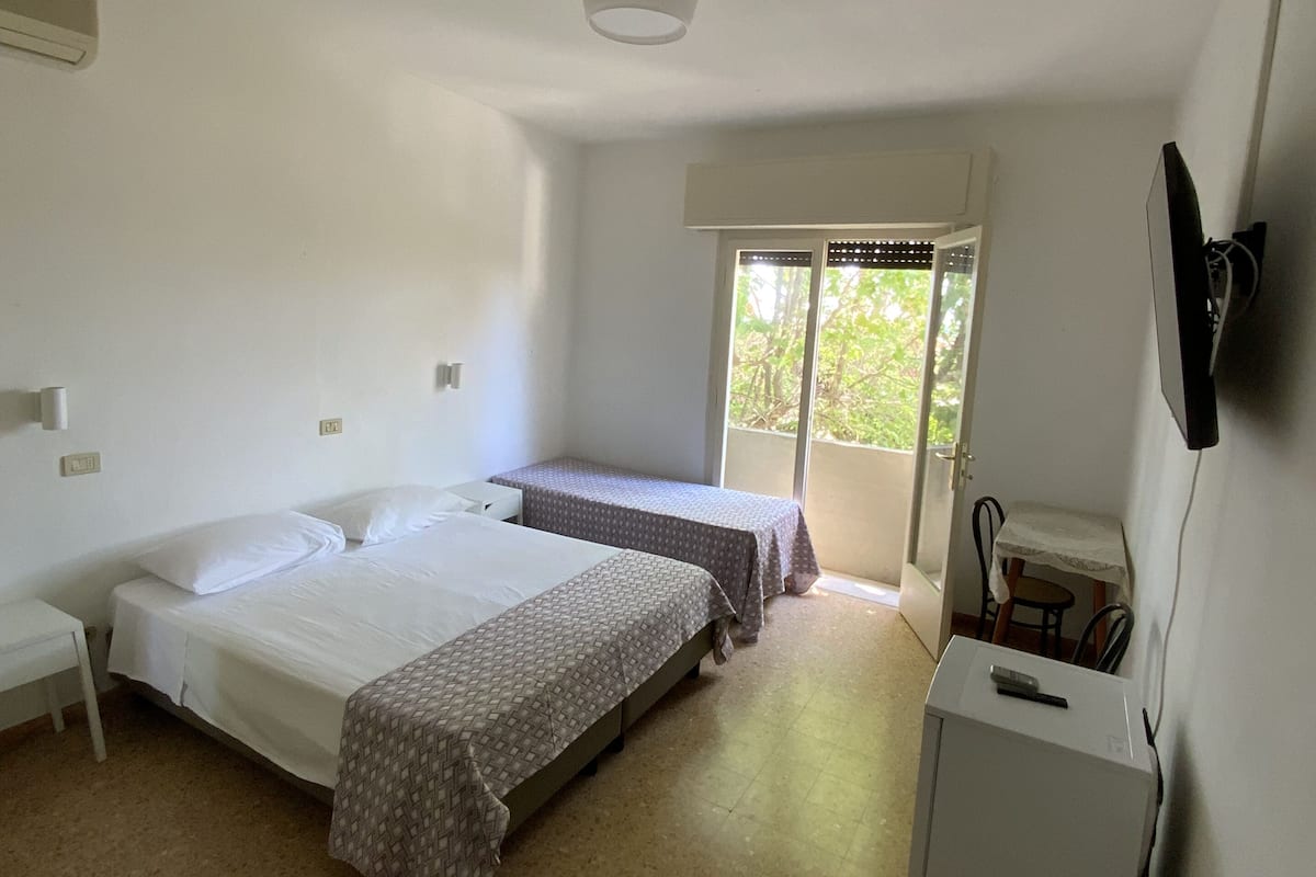 A room with two beds, a small table, and a refrigerator.
