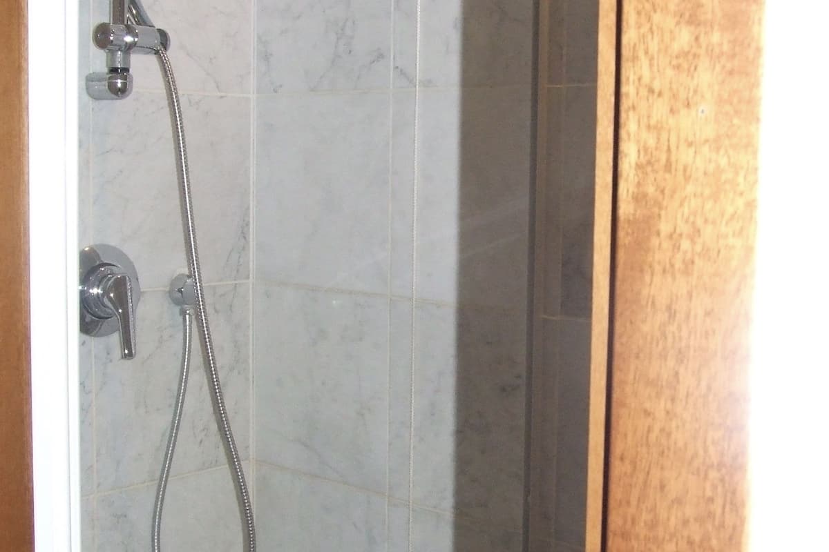 A shower with a handheld showerhead and a wall-mounted faucet.