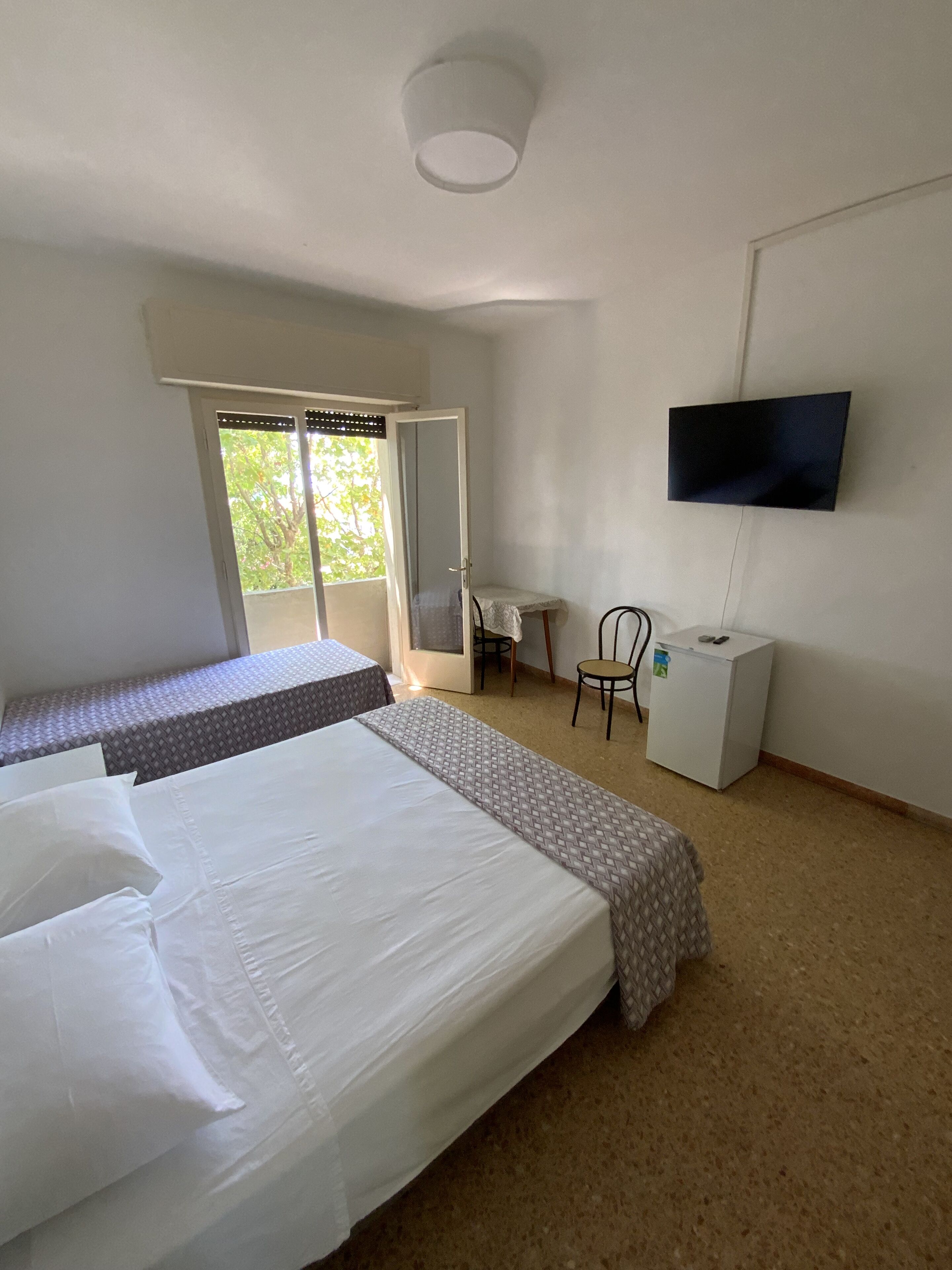 A hotel room with two beds, a television, a desk, and a chair.