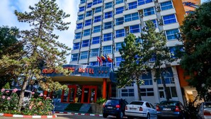 Un hotel de varios pisos con un diseño moderno, que cuenta con una entrada destacada y un área de estacionamiento al frente.