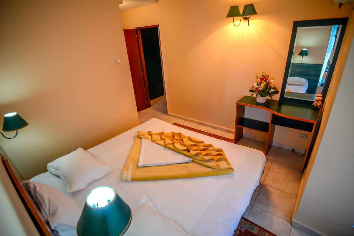 Une chambre d’hôtel avec un lit, une table de chevet, une lampe et un miroir.