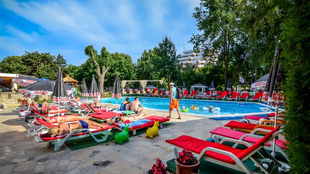 Un área junto a la piscina con sillas de descanso, una piscina y sombrillas.