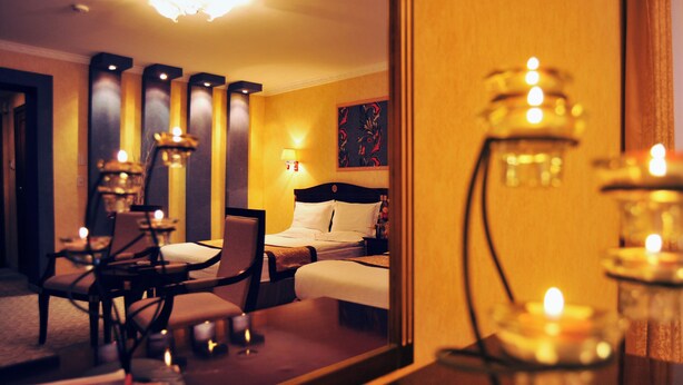 A hotel room with a bed, bedside table, lamp, and a mirror reflecting the room. - White House Hotel (Ulaanbaatar)