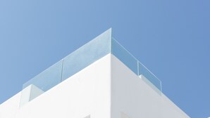 Een modern wit gebouw met een glazen balkon en grote ramen.