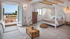 Een slaapkamer met een hemelbed, een houten kist en uitzicht op zee.