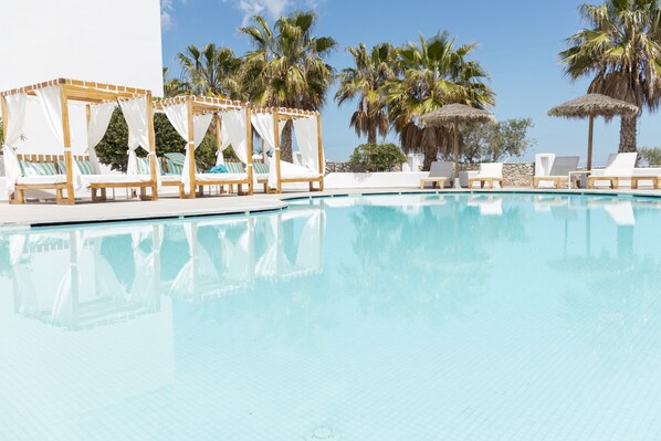 Una piscina al aire libre, sombrillas, sillones reclinables de piscina