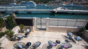 Une terrasse sur le toit avec des sièges extérieurs, une vue sur le port de plaisance et une entrée sécurisée par un portail.