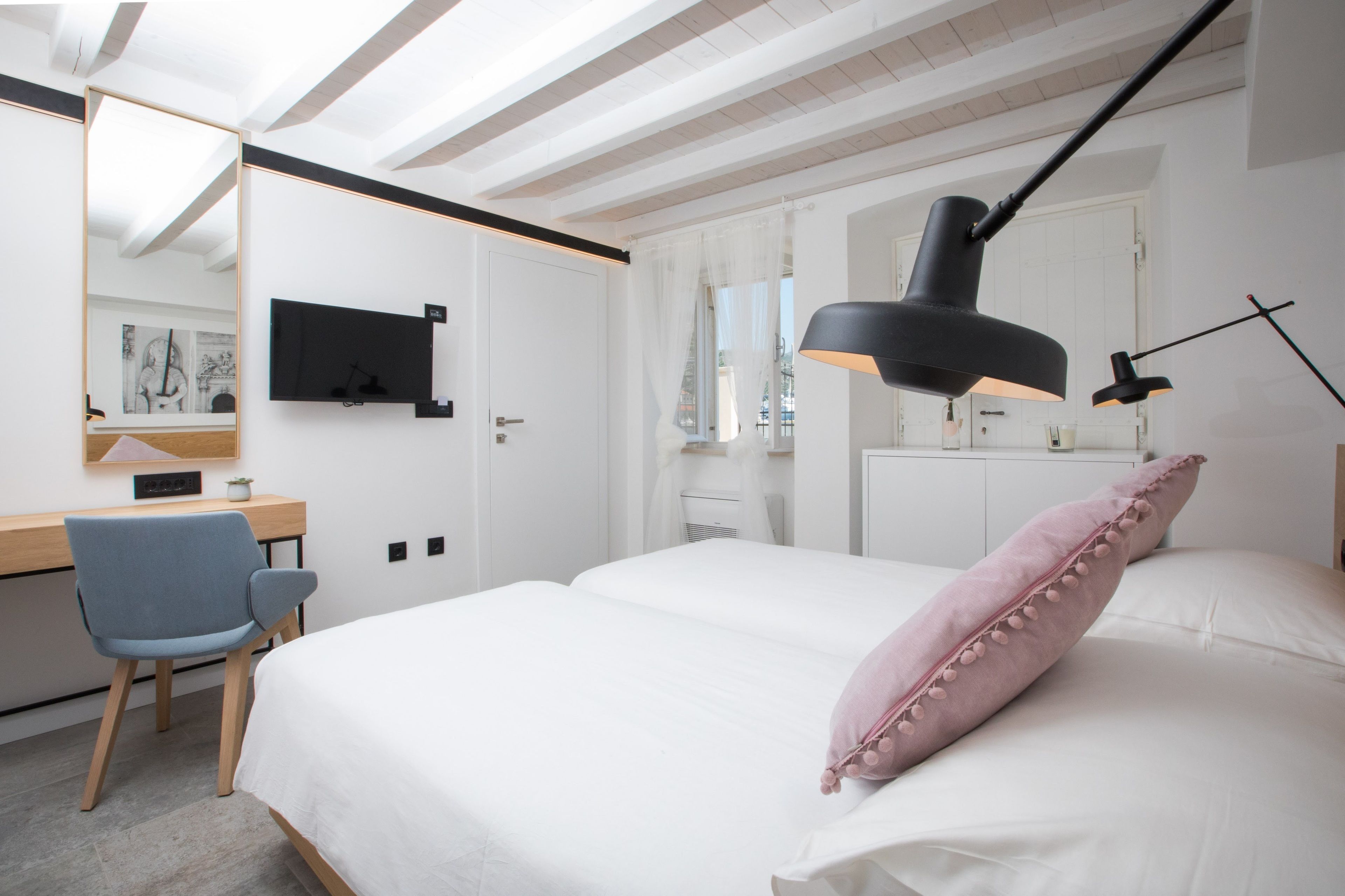Un dormitorio moderno con cama, escritorio, silla y televisor montado en la pared.