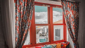 A red-framed window with a view of a swimming pool and a building. - Narcicegi Alacati (Cesme)