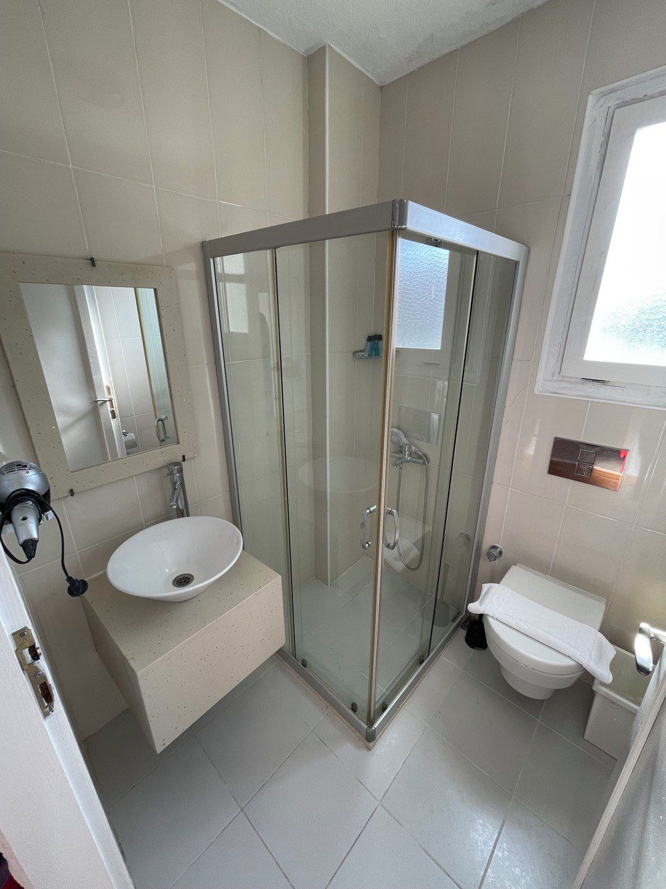 A bathroom with a glass-enclosed shower, a sink, and a toilet.