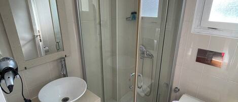 A bathroom with a glass-enclosed shower, a sink, and a toilet.