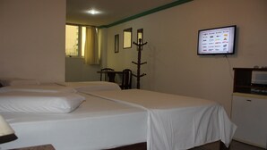 A hotel room with two single beds, a desk, a chair, a coat rack, and a television mounted on the wall. - Hotel Pousada da Praça (Recife)